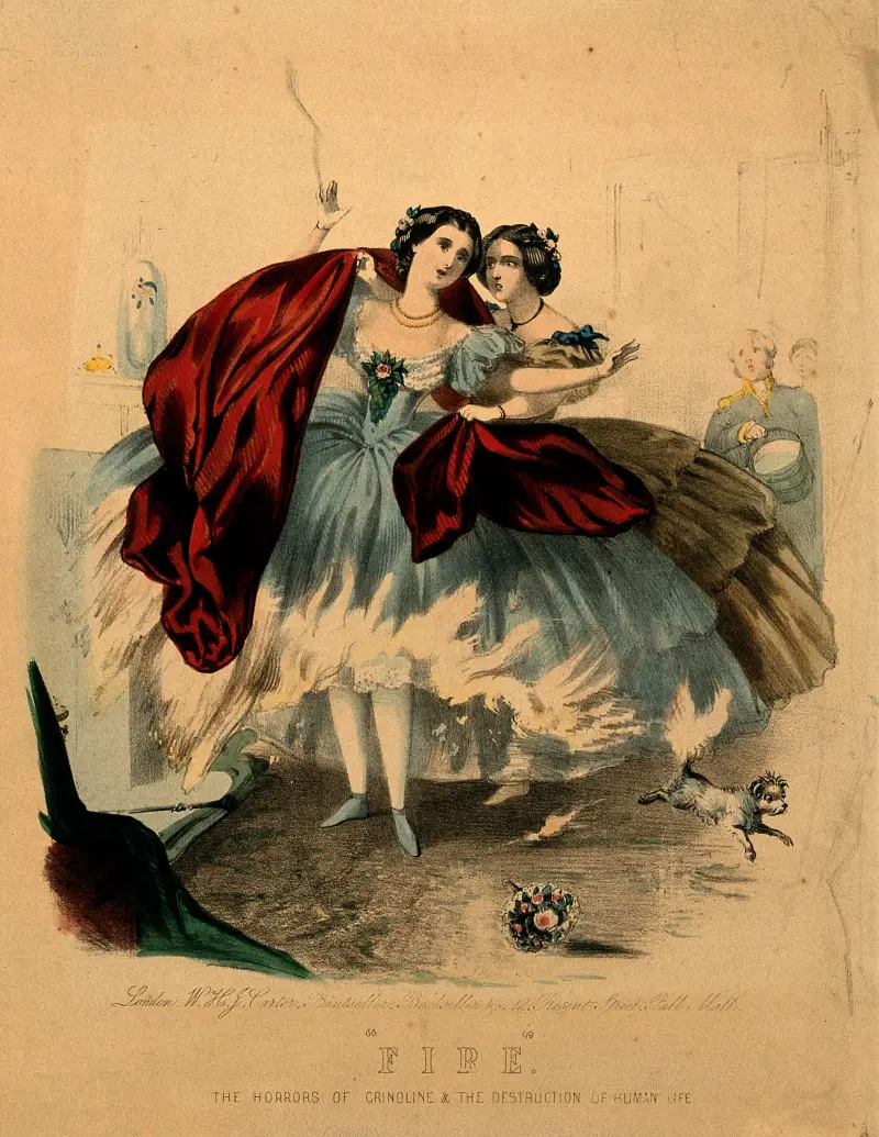 Eine kolorierte Lithografie von etwa 1860: Der weite Krinolinenrock einer Frau brennt neben einem Kamin, während eine zweite Frau sie mit einem roten Tuch bedeckt, mit dem Titel „Feuer. Die Schrecken der Krinoline & die Vernichtung menschlichen Lebens“ (Wellcome Collection, gemeinfrei)