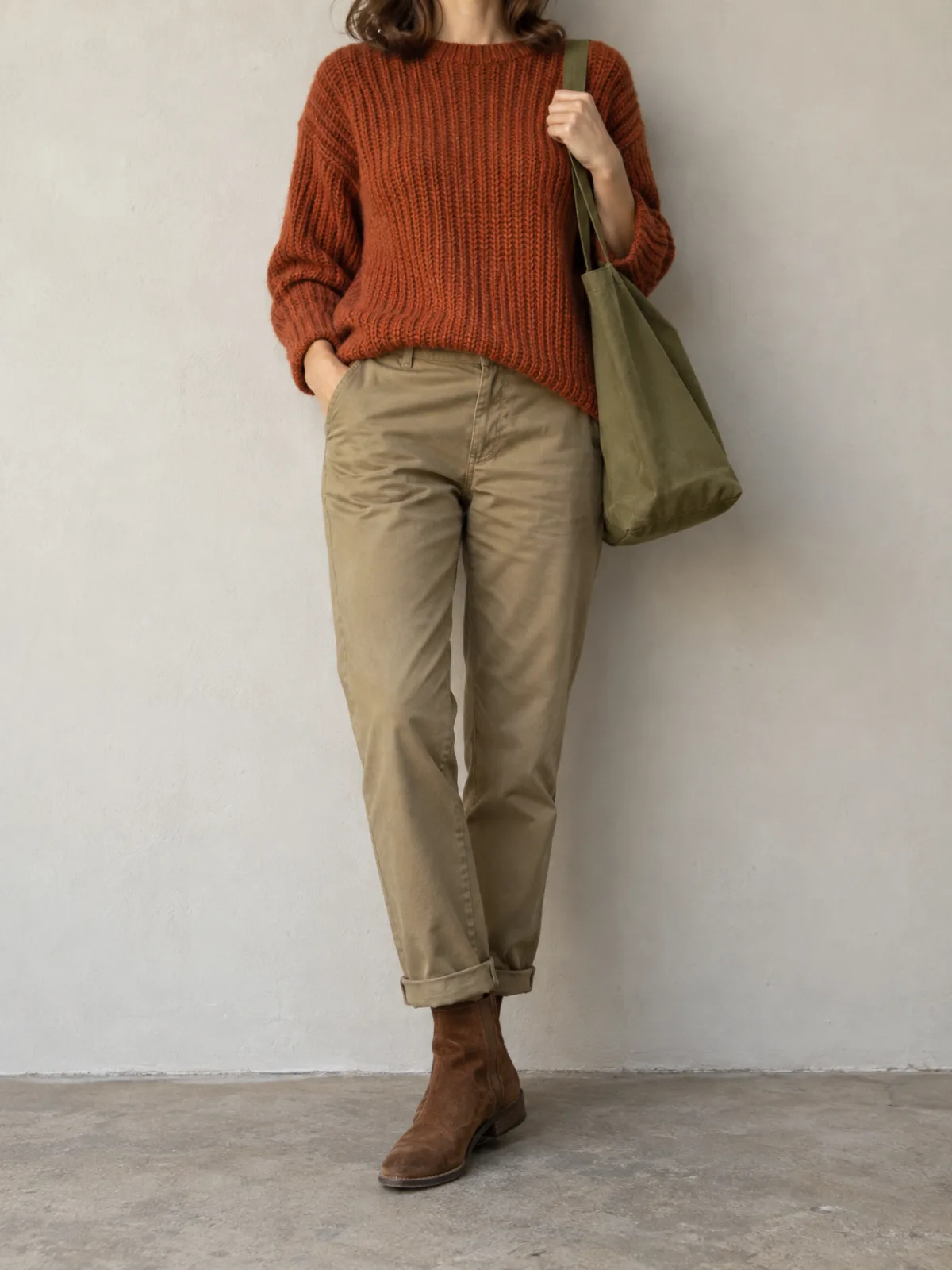 Warm Autumn weekend outfit: rust knit sweater, khaki chinos, brown suede boots and an olive canvas bag